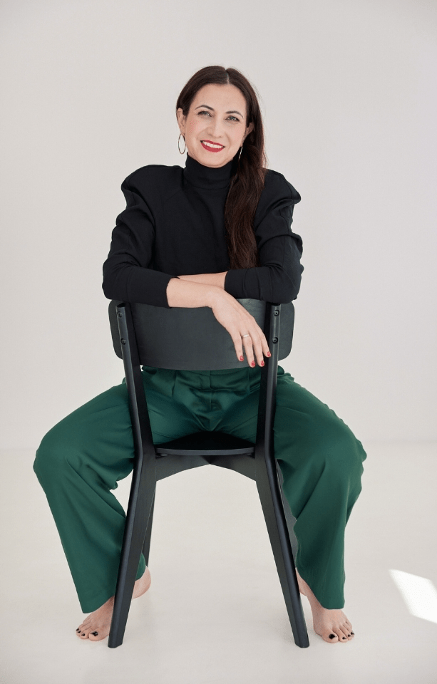 Wizerunek eleganckiej bosej kobiety siedzącej na odwróconym krześle.